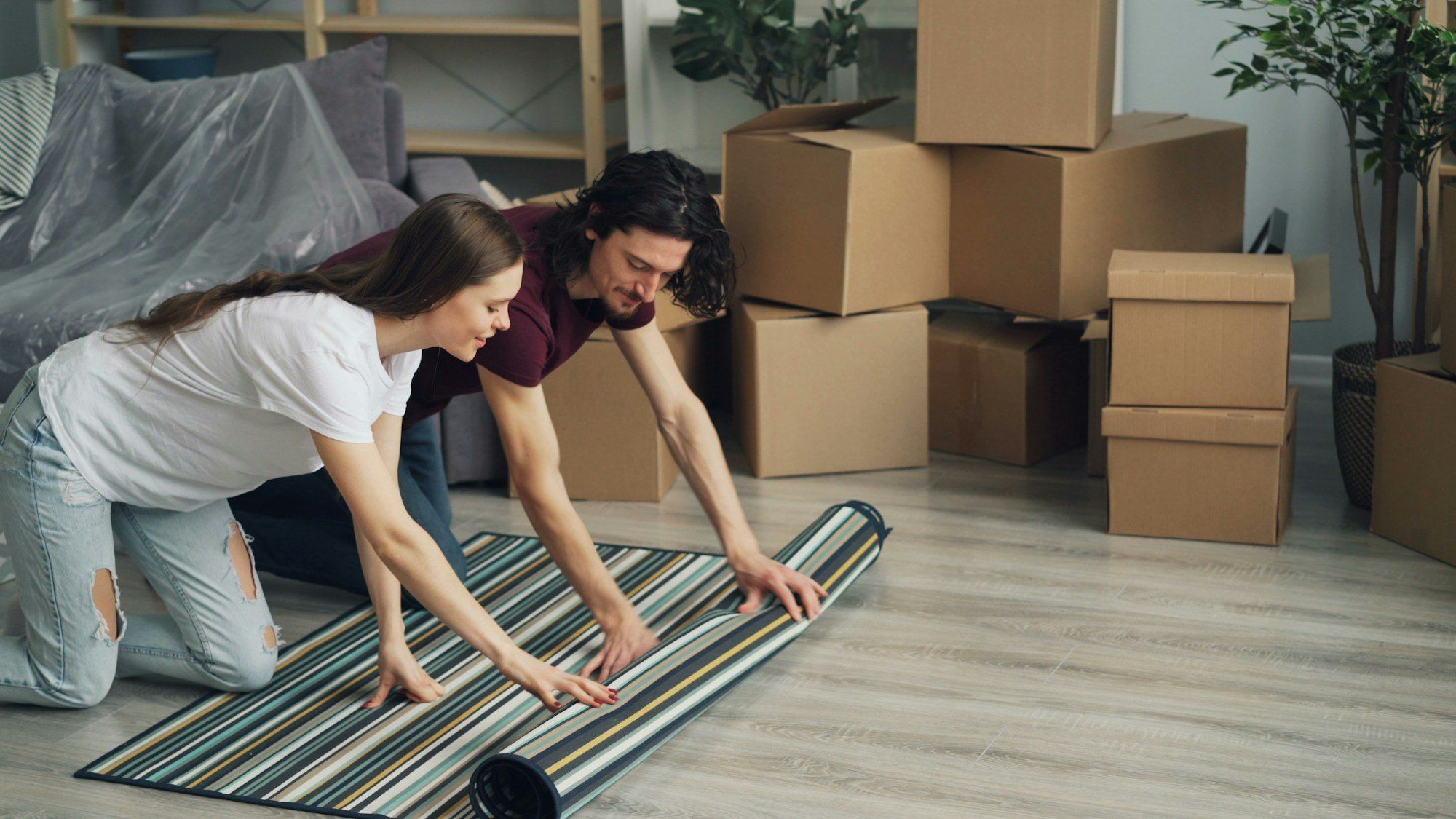 Couple déroulant un tapis dans son nouveau logement